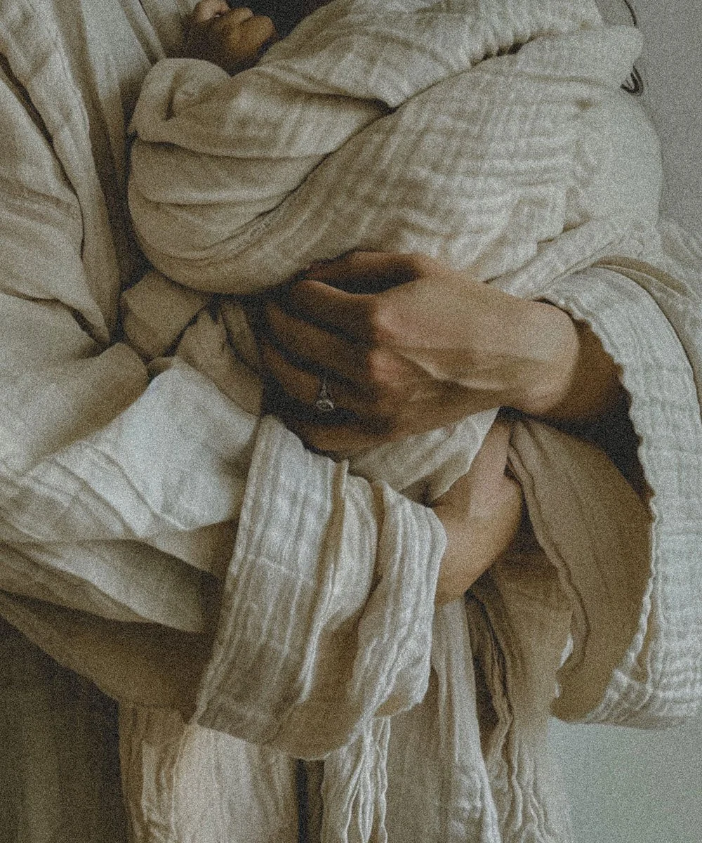 newborn baby being held in between hands