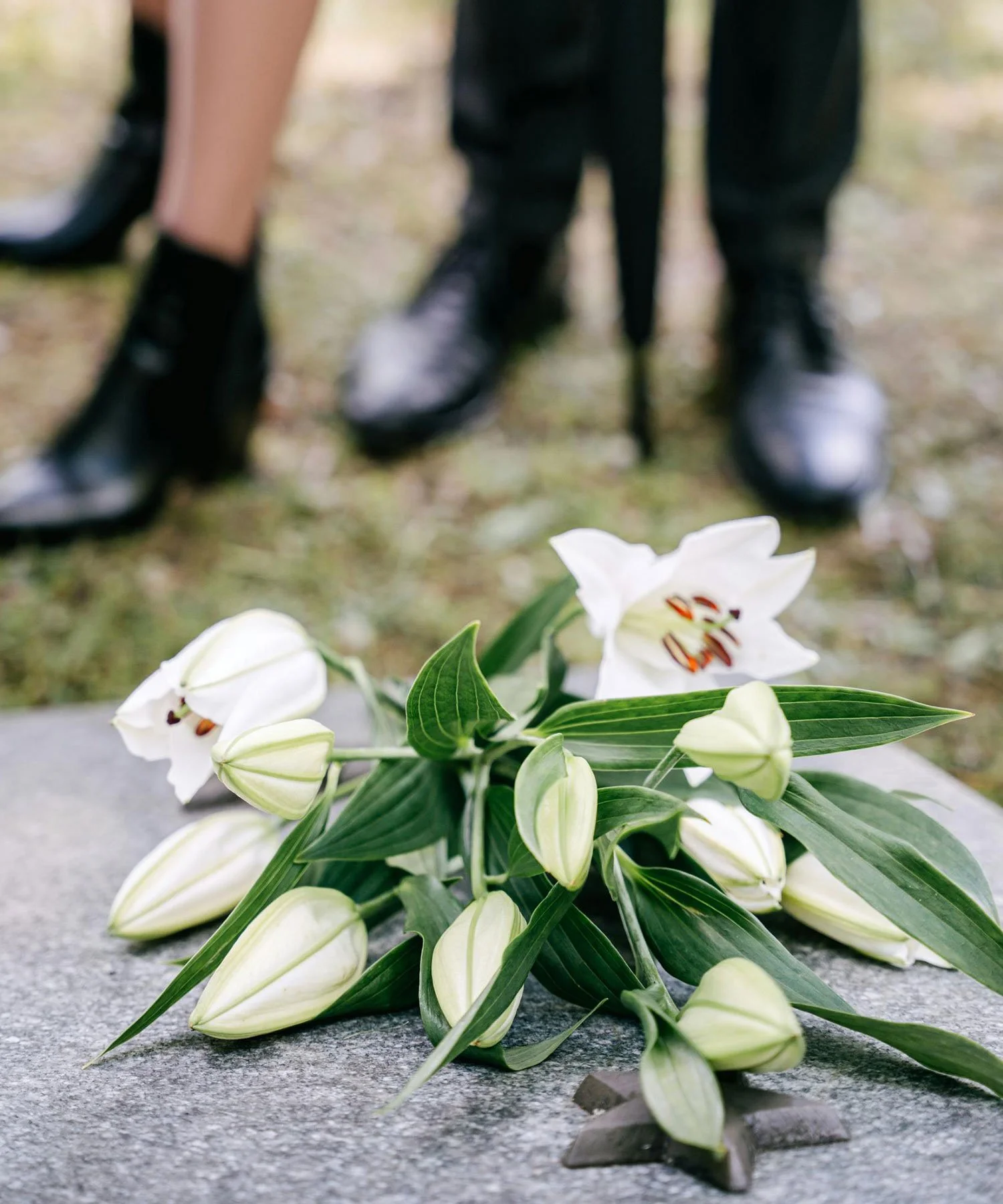 White flowers sitting on the ground in a cemetery.
