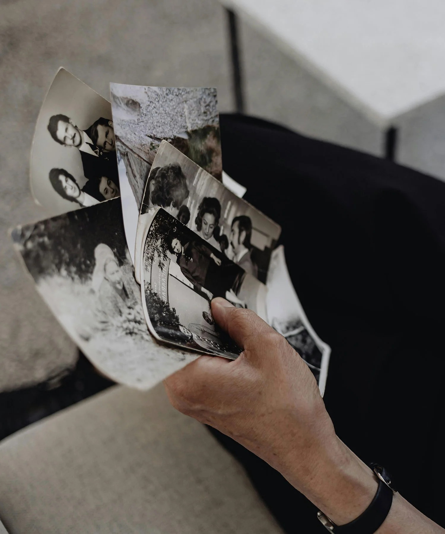 An older handing holding old black and white photos of a family member.