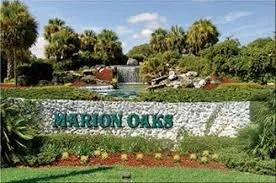 Sign that reads 'Marion Oaks' in front of a landscaped area with trees, flowers, and a small fountain