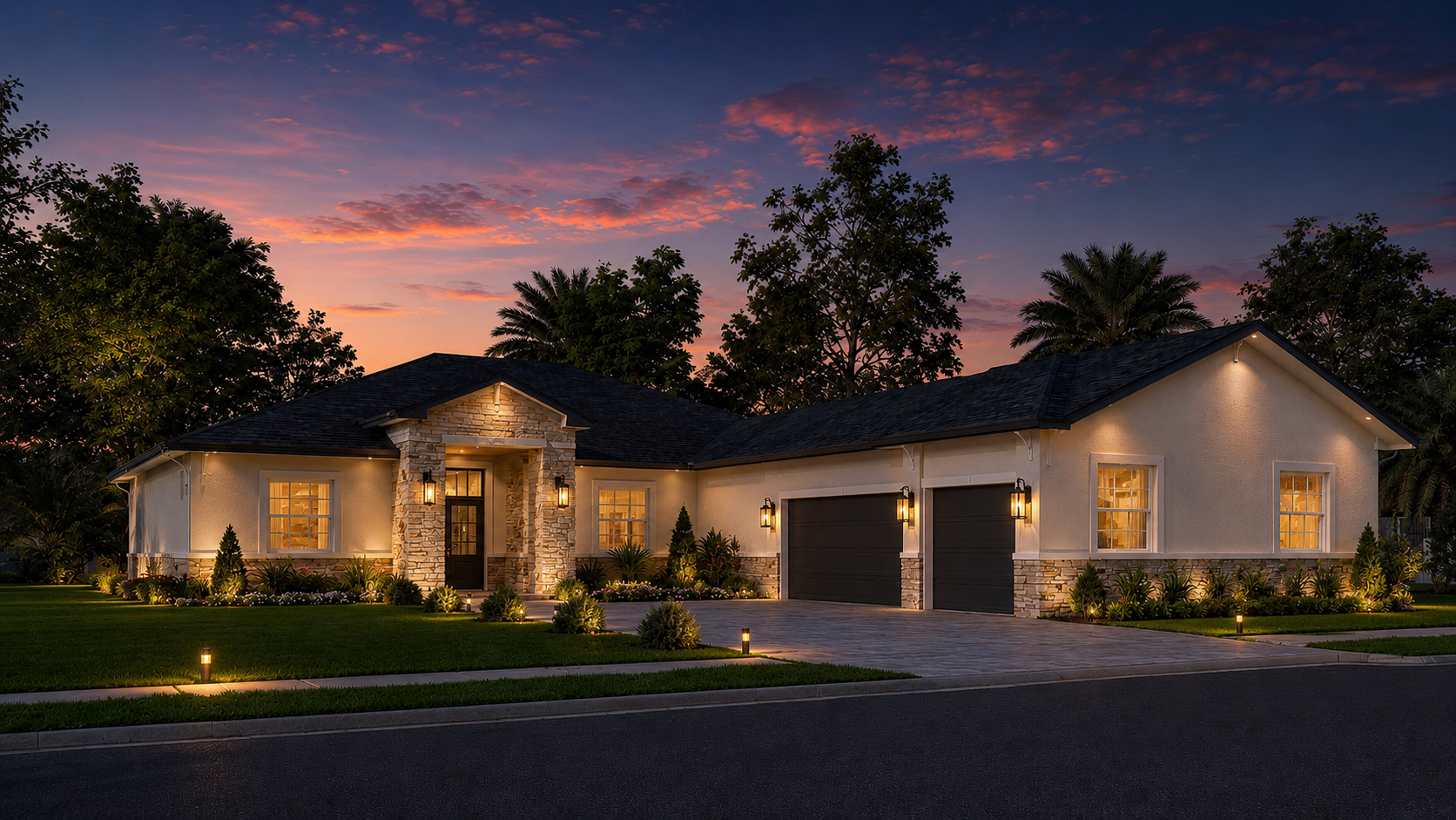A modern single-story house at dusk with exterior lighting, landscaped lawn, paved driveway, and trees in the background under a colorful sunset sky.