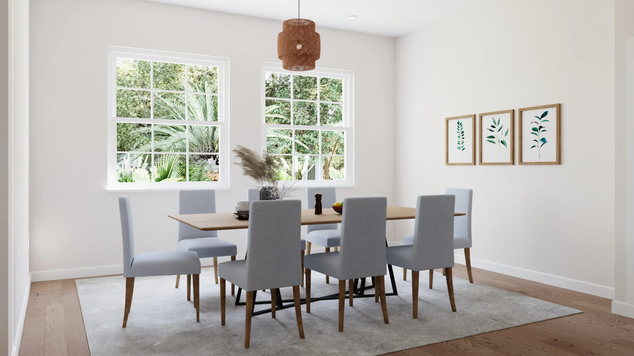A bright dining room with a wooden table and eight light gray upholstered chairs. Two windows show green foliage outside. Simple wall art with botanical prints is on the wall. A woven pendant light hangs above the table, which has a vase with pampas 