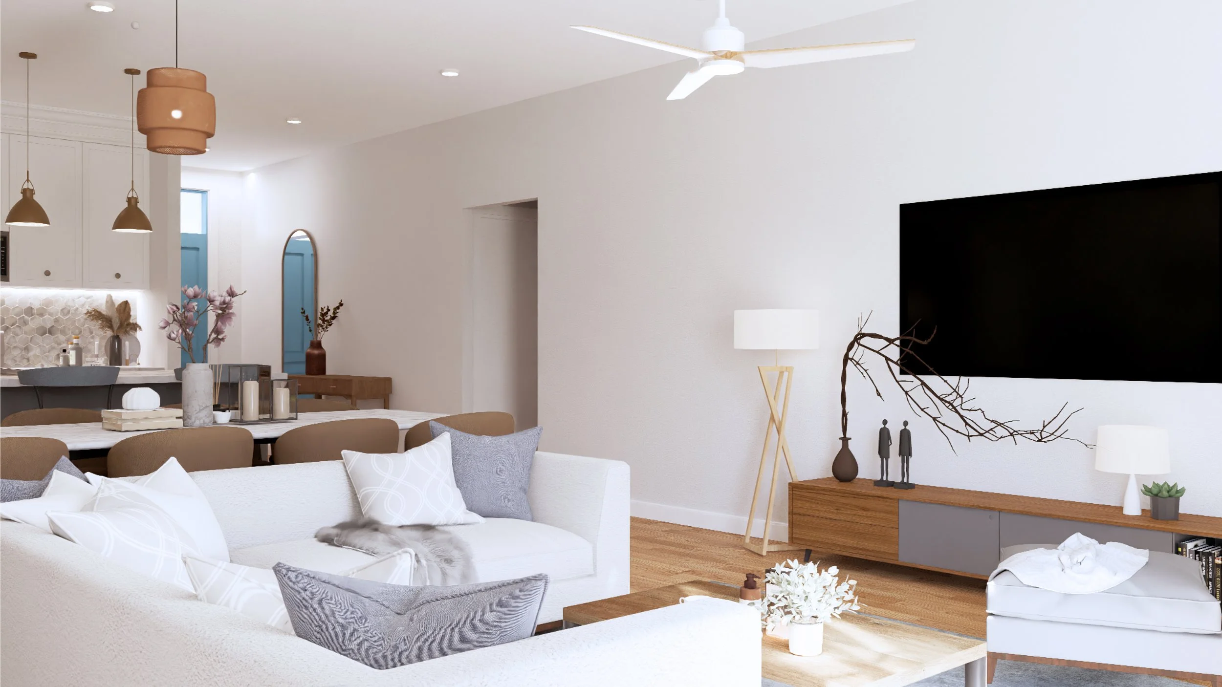 A modern, minimalist living room with a white couch, pillows, a wooden TV stand, a flat-screen TV, decorative vases with branches, a floor lamp, and a white chair with a blanket. The space is bright with natural light and has a wooden floor.