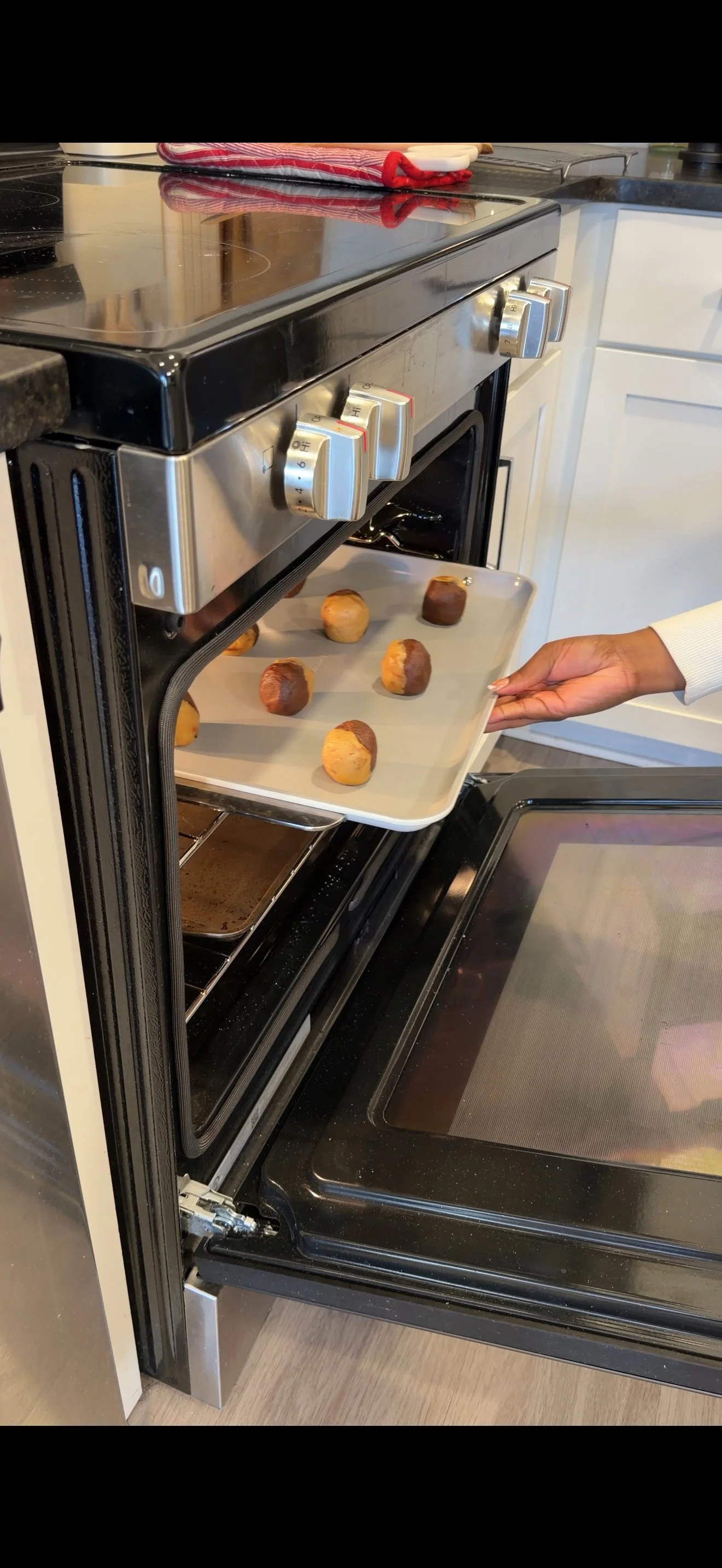 cookie dough on baking sheet being slid into oven for baking. 
