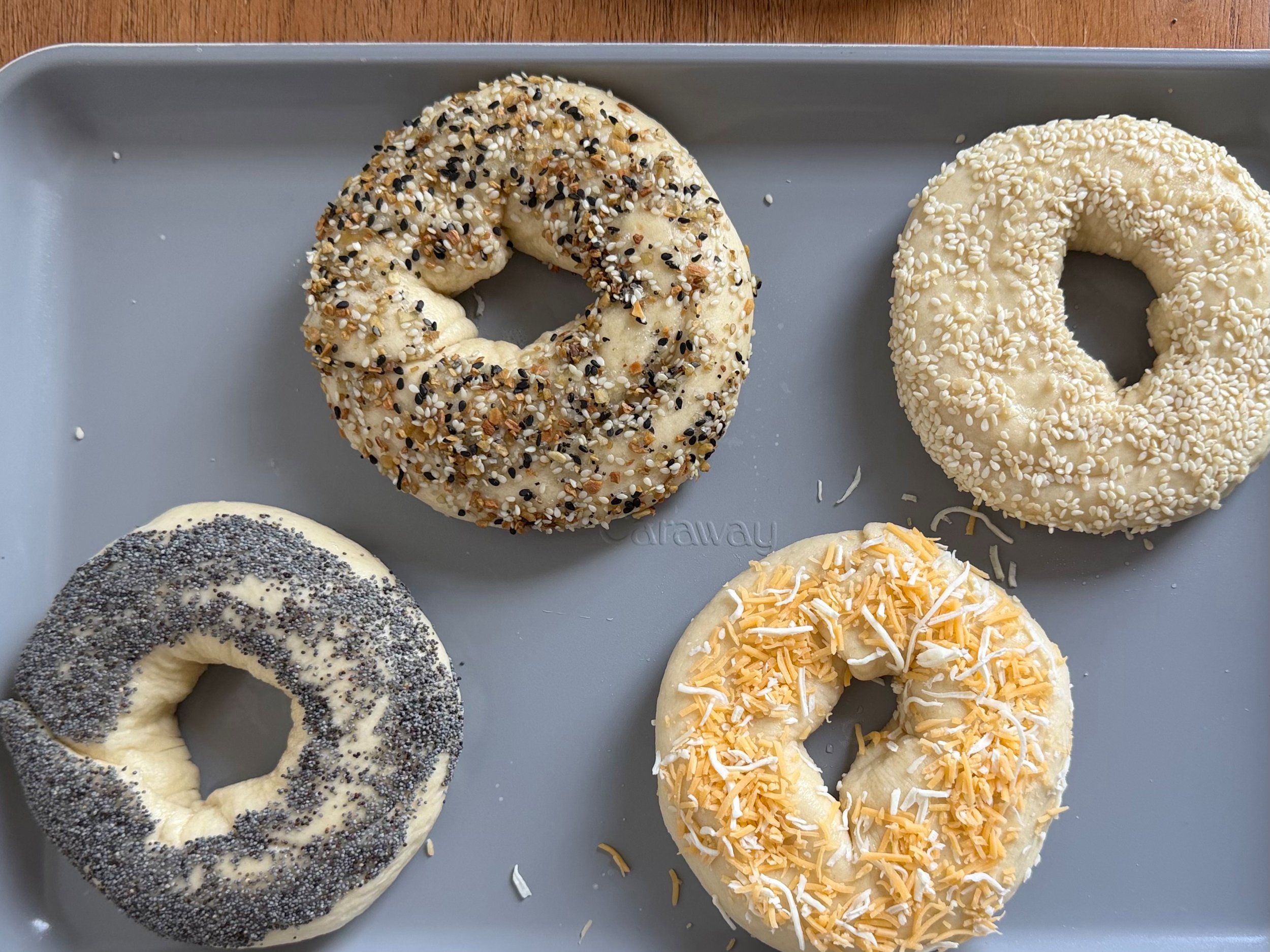 four bagels with toppings on baking sheet ready to be baked. 
