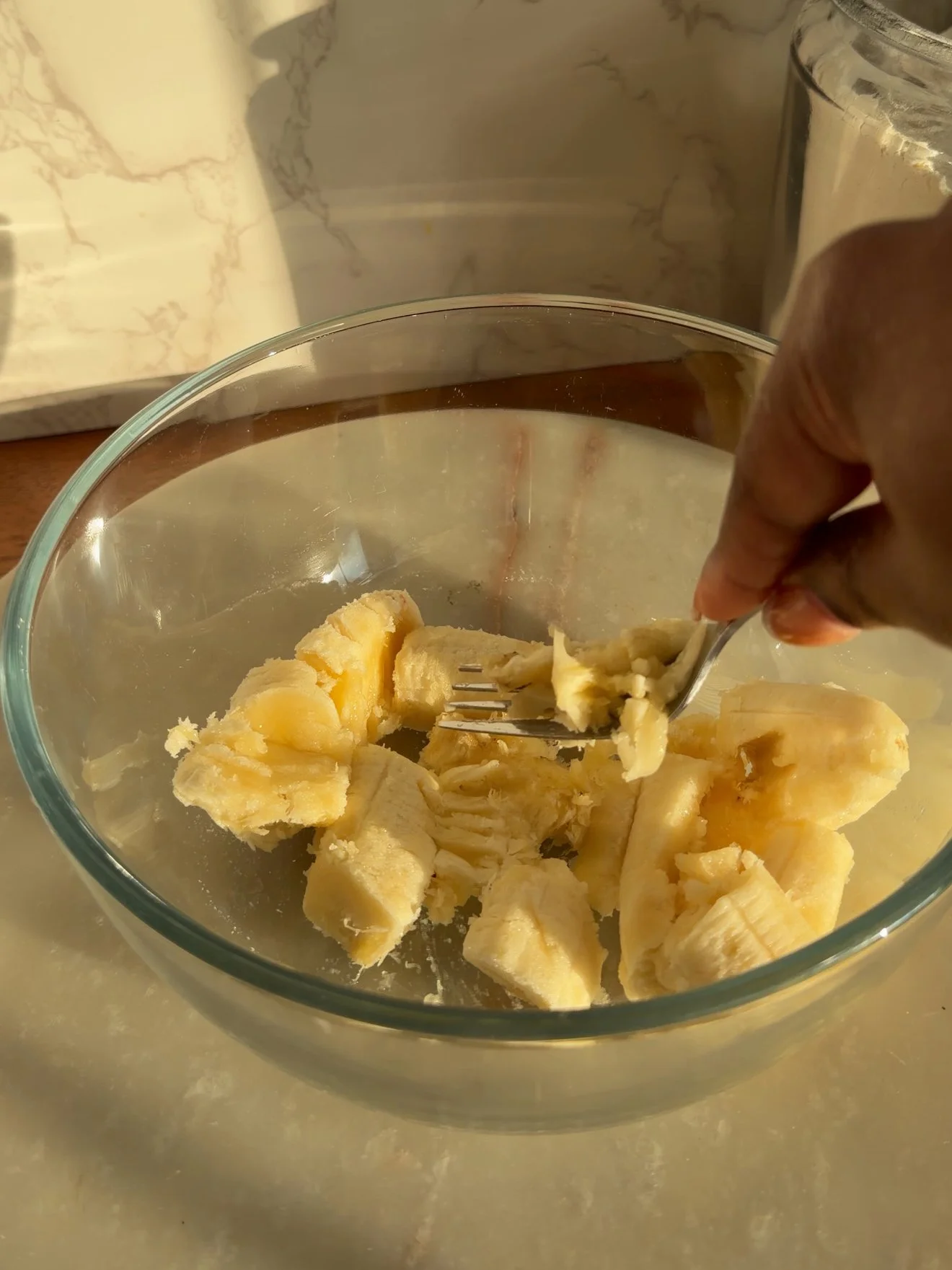 banana being mashed with fork in glass mixing bowl