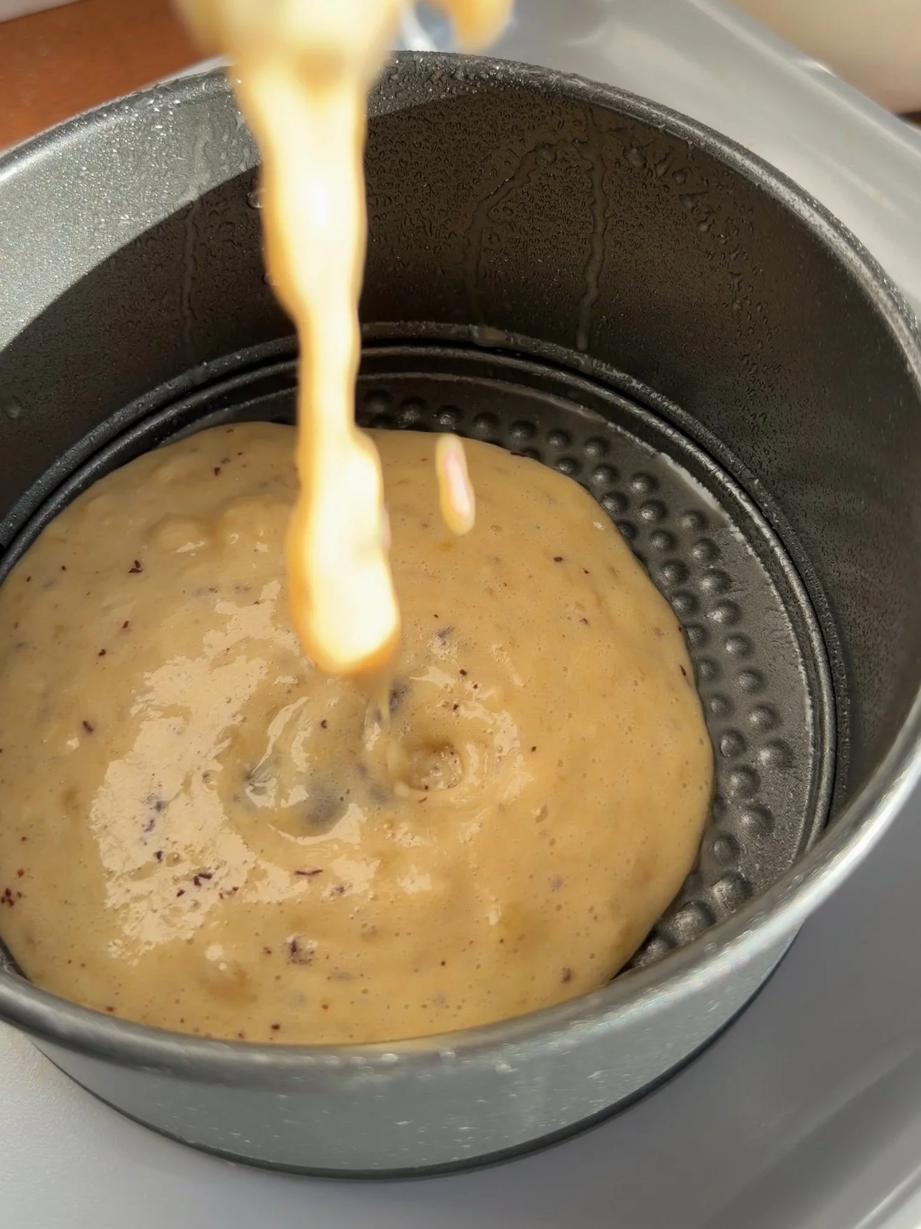 batter being poured into six inch cake pan