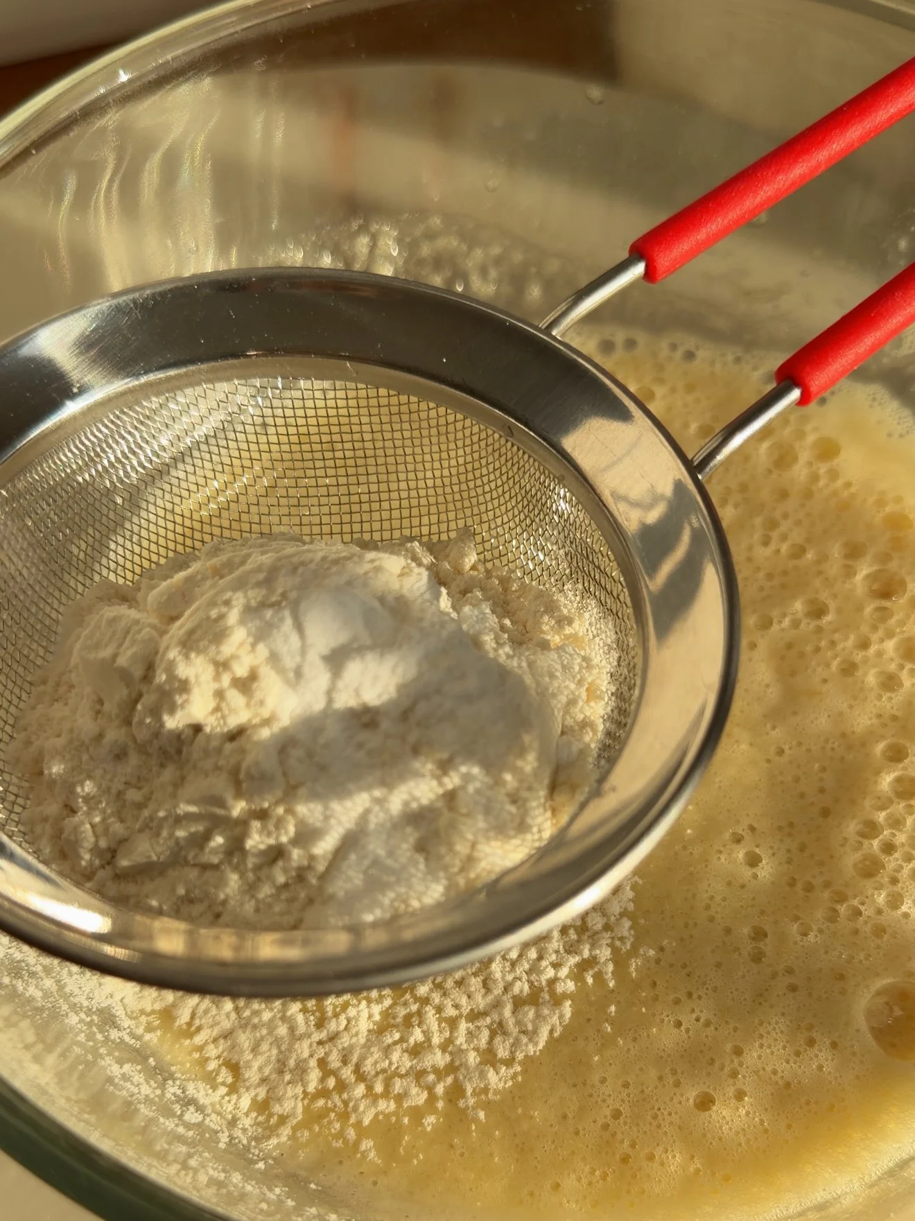 dry ingredients being sifted into wet ingredients. 