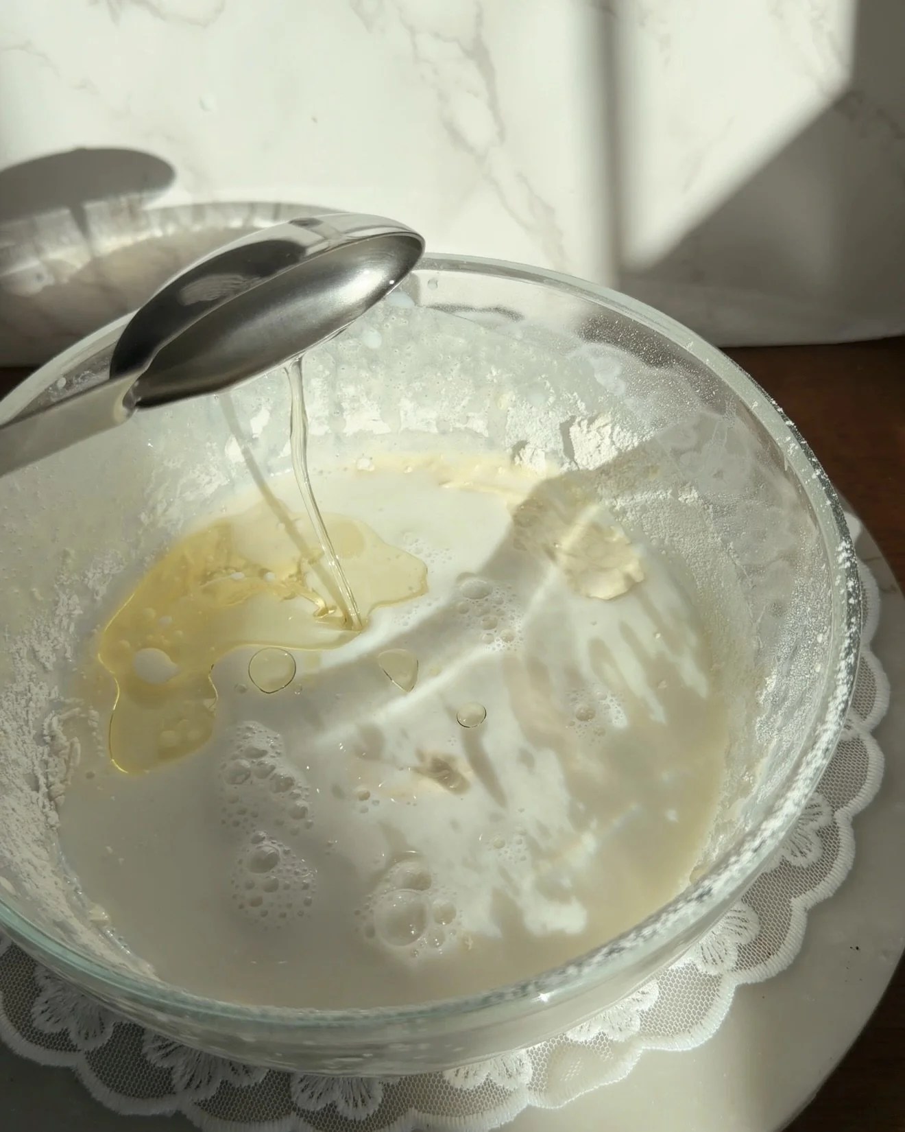 Oil being poured into glass mixing bowl with of cake batter