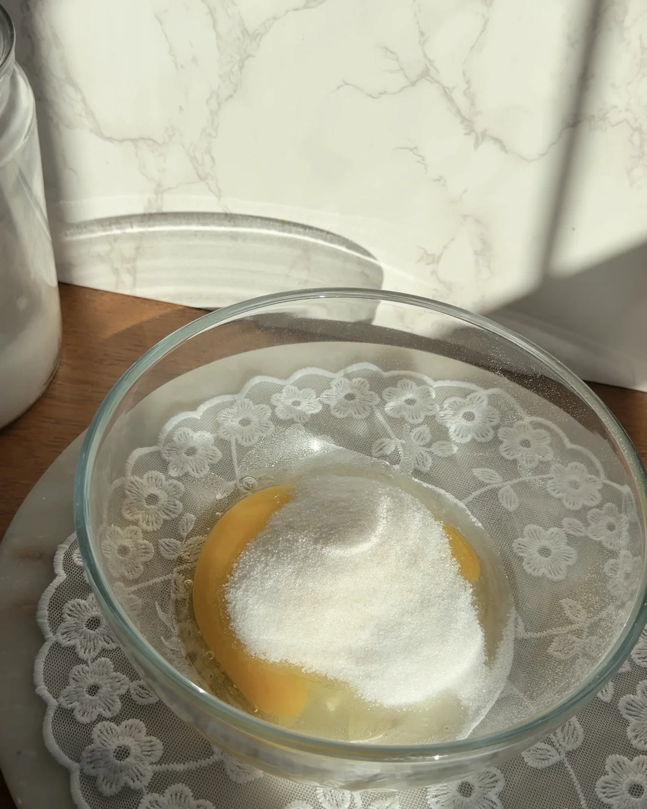 glass mixing bowl with egg and granulated sugar