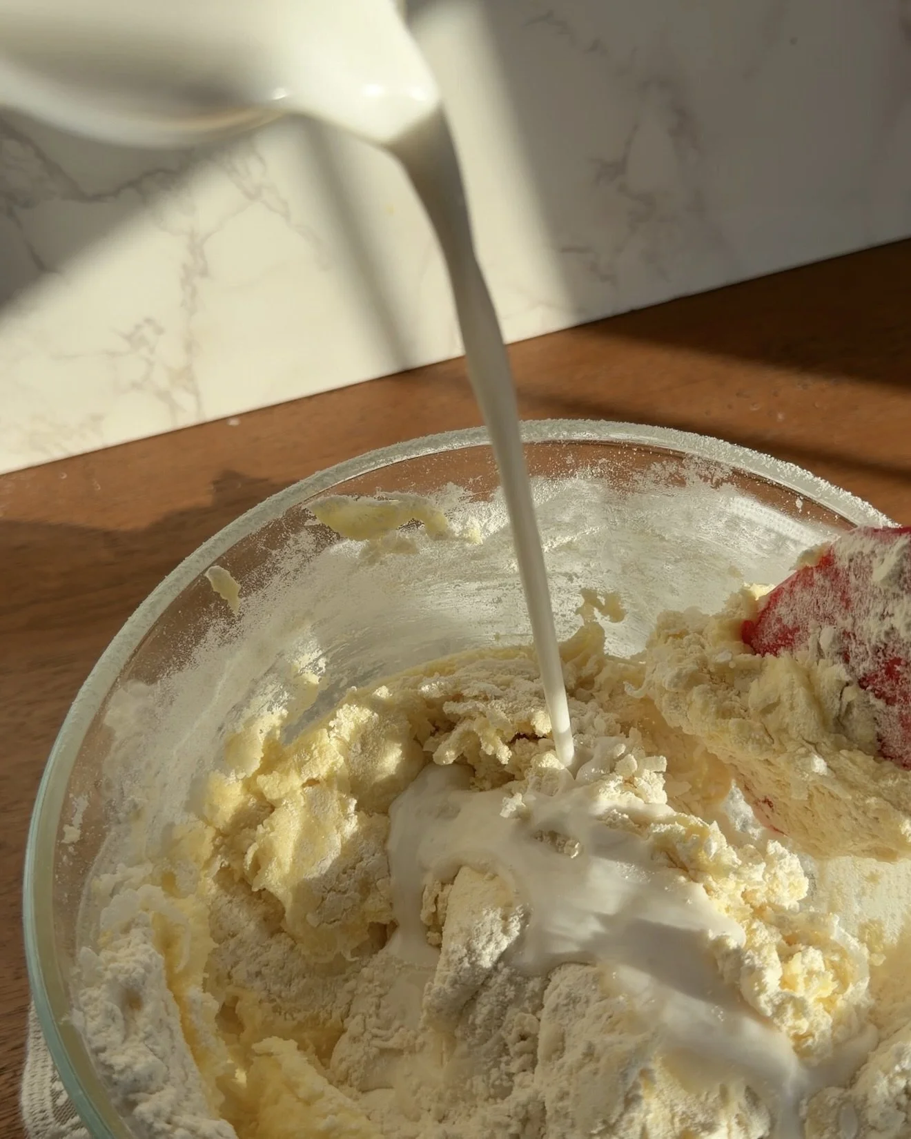 Coconut milk being added for frosting in a mixing bowl