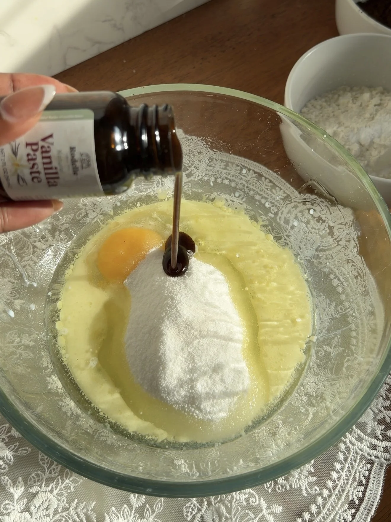 Vanilla being added to mixing bowl on the counter with wet ingredients. 