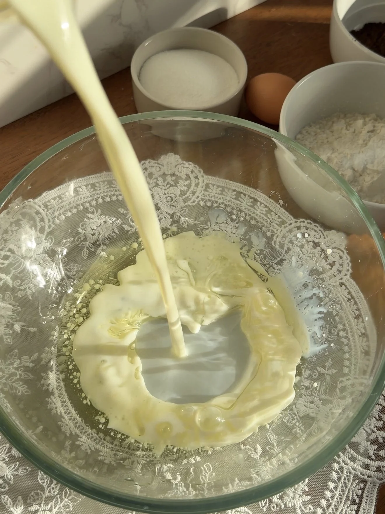 Glass mixing bowl on the counter with milk and oil