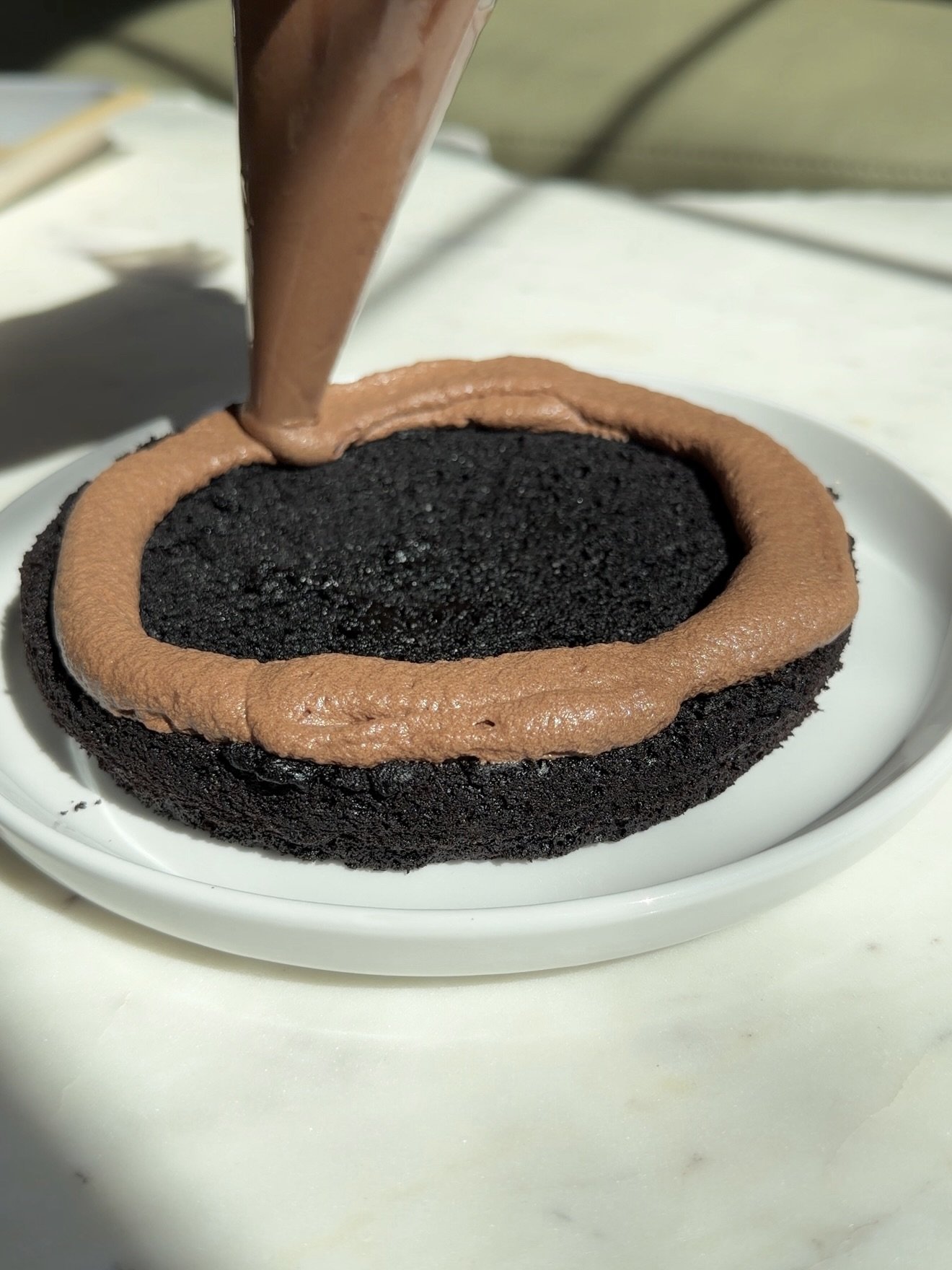 Chocolate cake being frosted with whipped chocolate ganache.