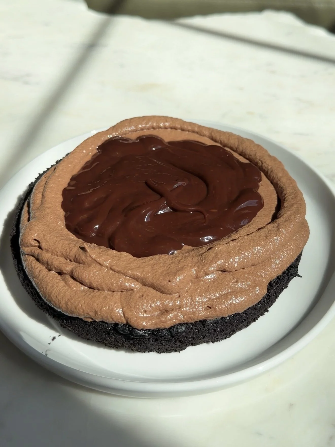 Chocolate cake being filled with regular chocolate ganache. 
