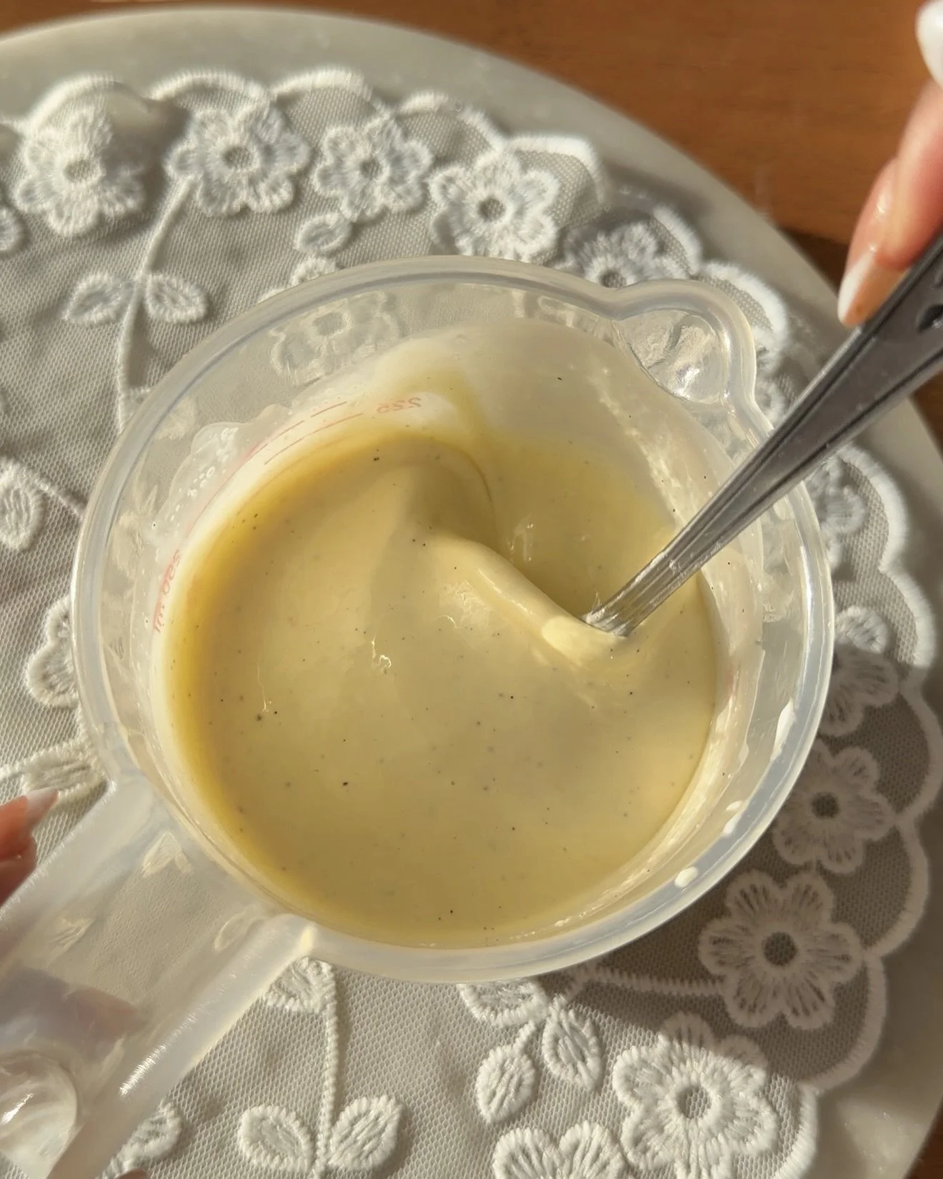 Plastic measuring cup on countertop being stirred with metal fork. 