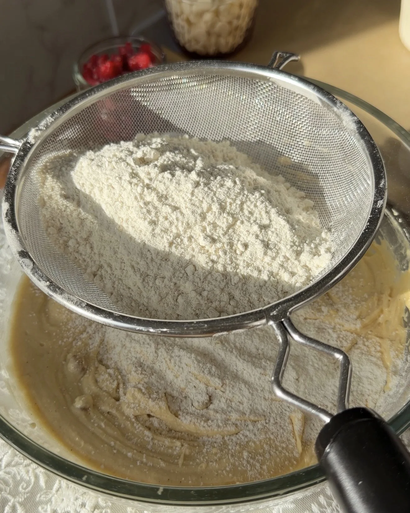 Dry ingredients being sifted into wet ingredients. 