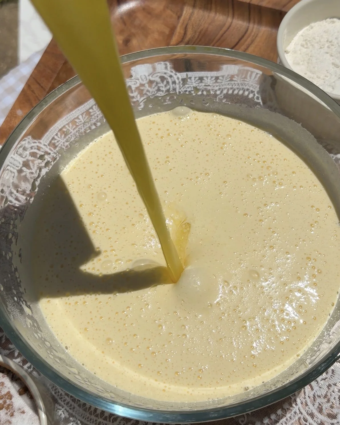 melted butter being poured into egg and sugar mixture in mixing bowl