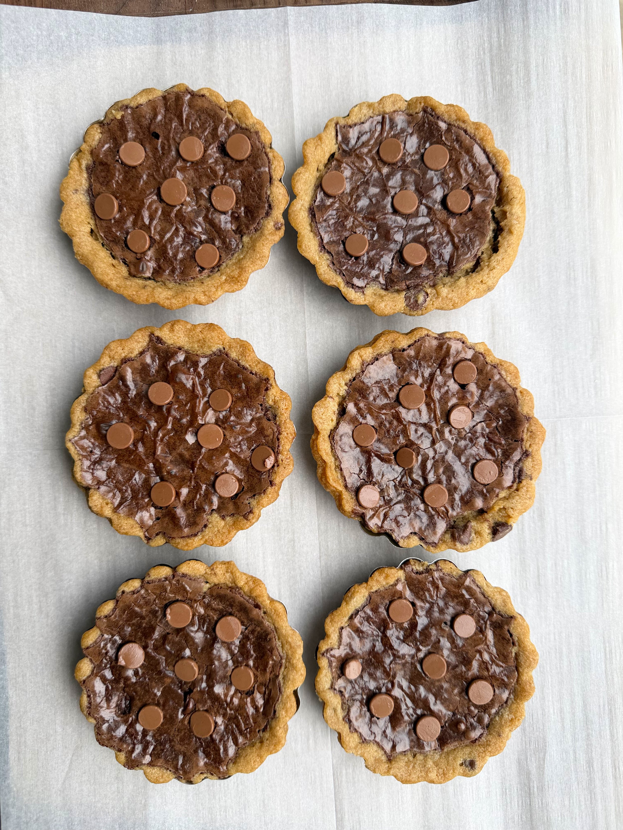 six cookie dough tarts on white parchment paper. 