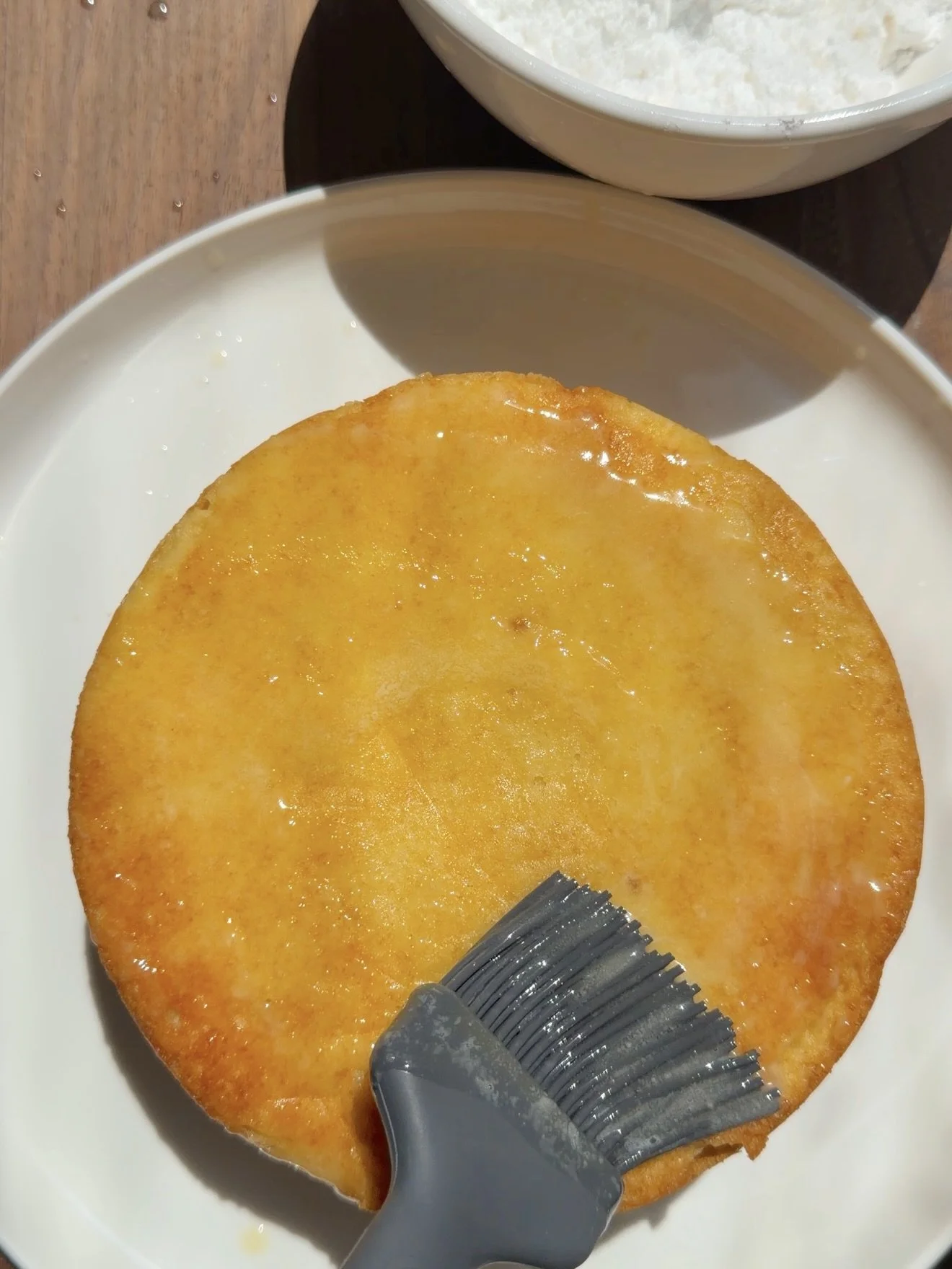 Baked cake being brushed with melted butter with grey silicone baking brush