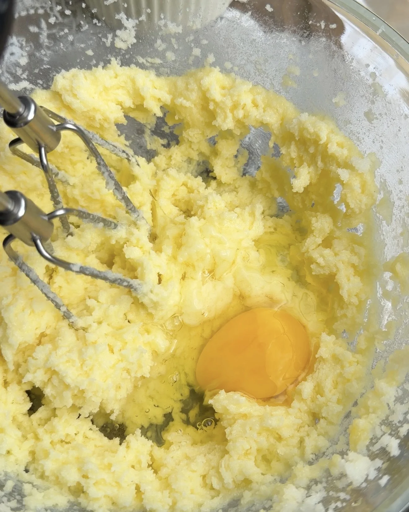 Butter and egg being beaten in glass mixing bowl