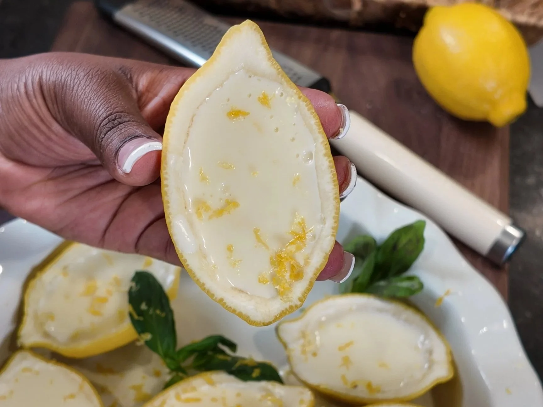 Silky lemon posset served in hollowed lemon shells on a marble surface