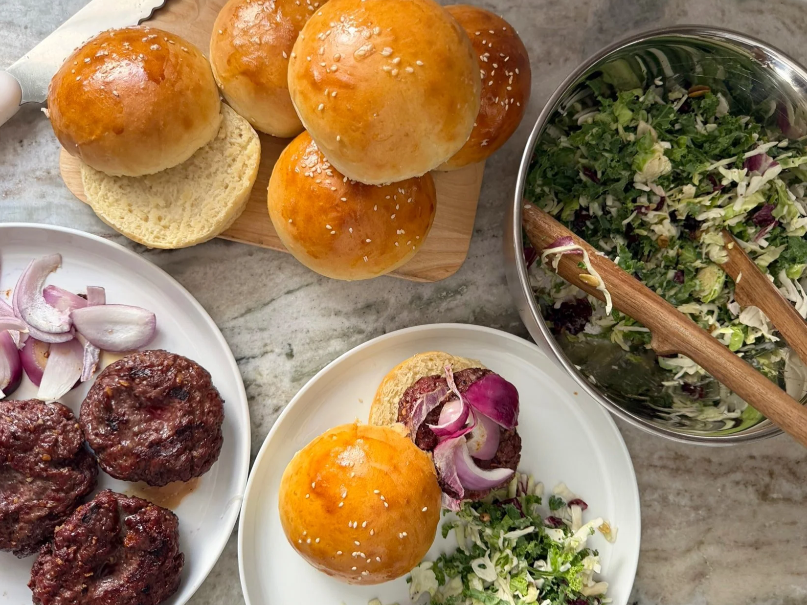 hamburger buns, patties, and salad on counter