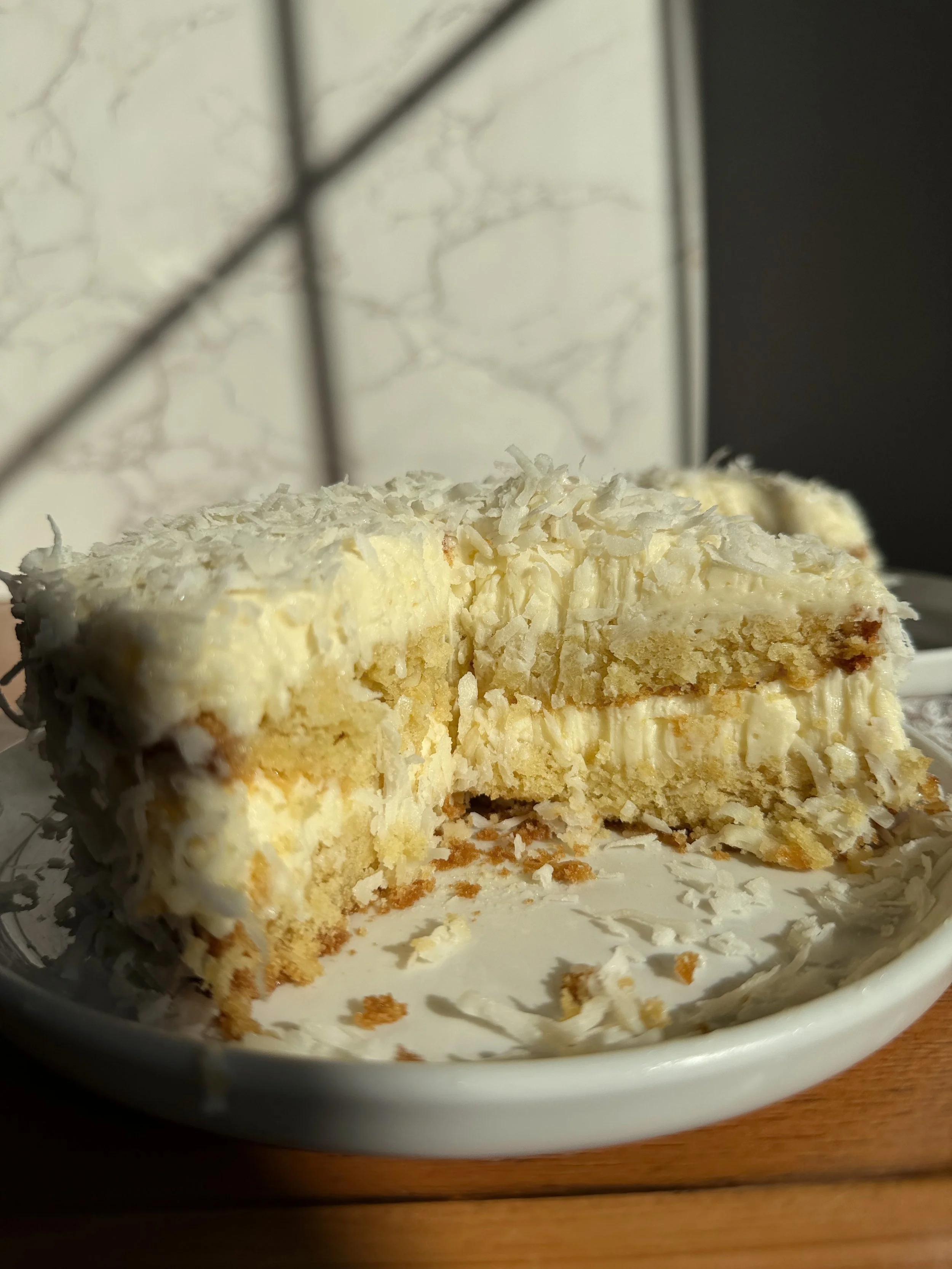 Cut Mini six inch coconut cake with coconut buttercream and flakes on top