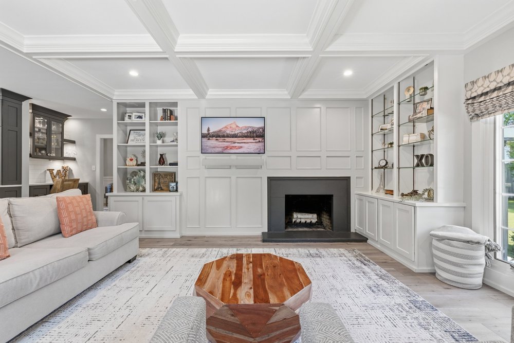 Living room with a coffered ceiling, fireplace, and built-in shelving