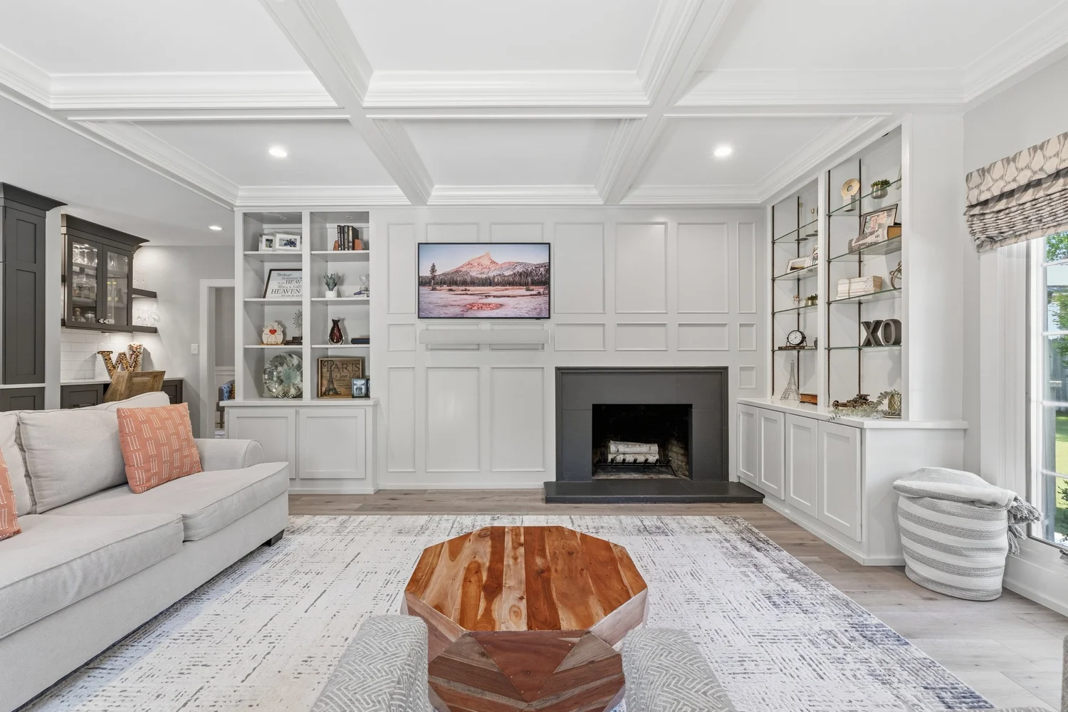 Bright living room with a coffered ceiling, fireplace, and built-in shelving