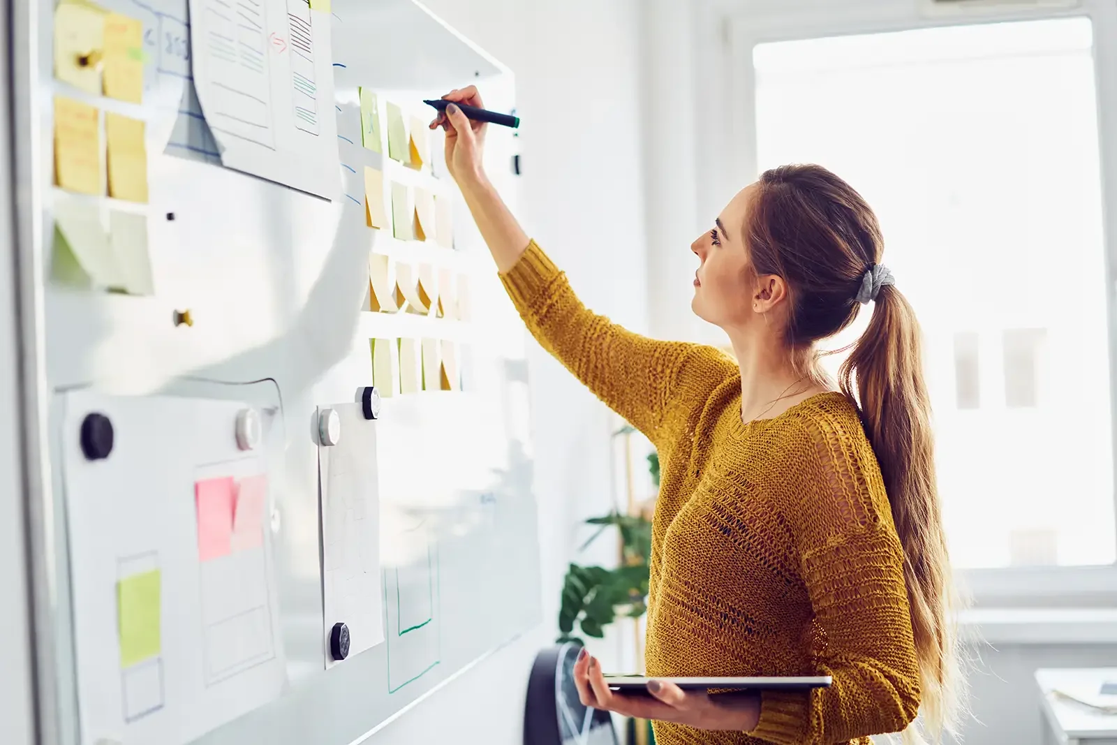 Sustainability professional at a white board strategizing and working on stakeholder reports and executive content