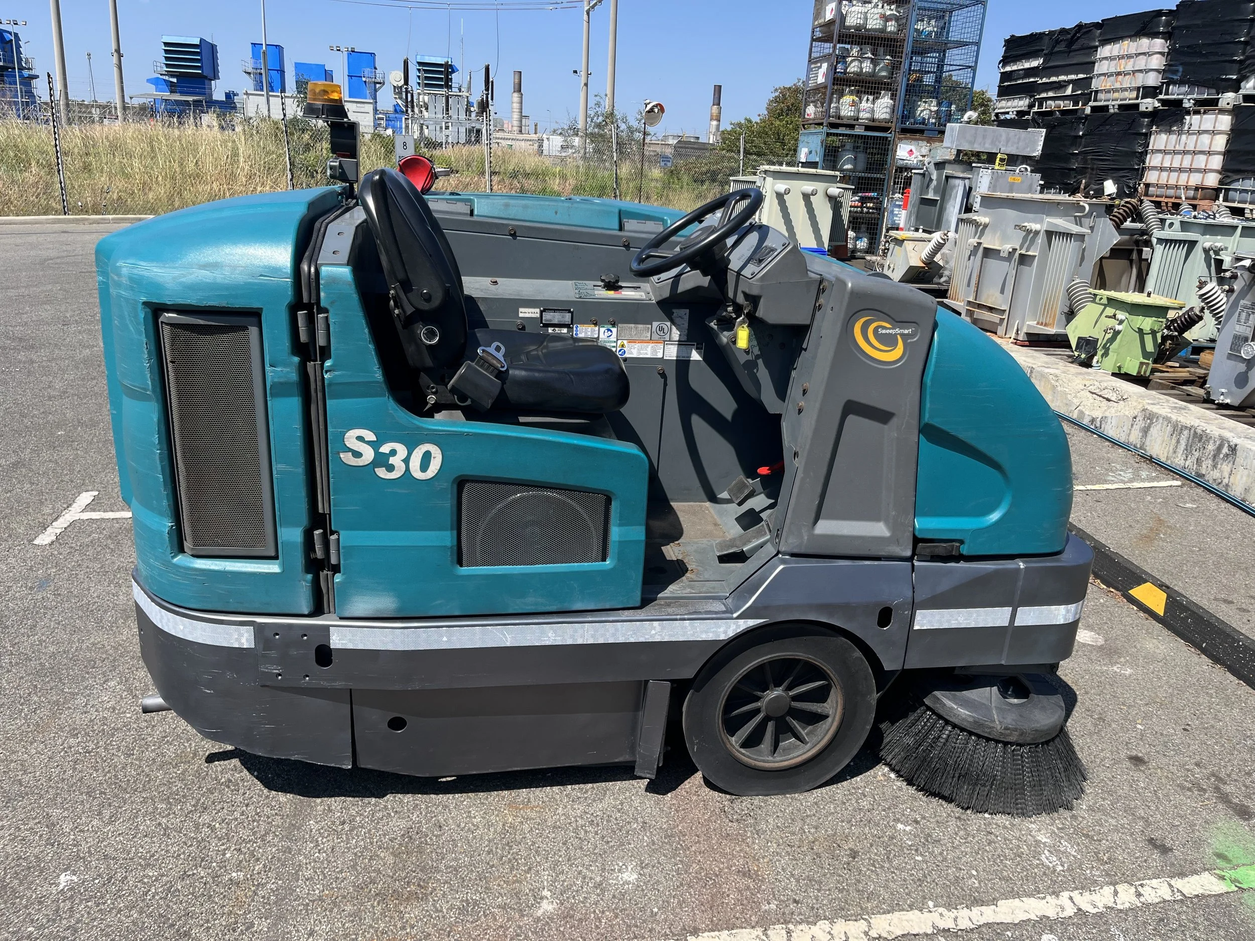 Industrial floor sweeper parked outdoors in an industrial area.