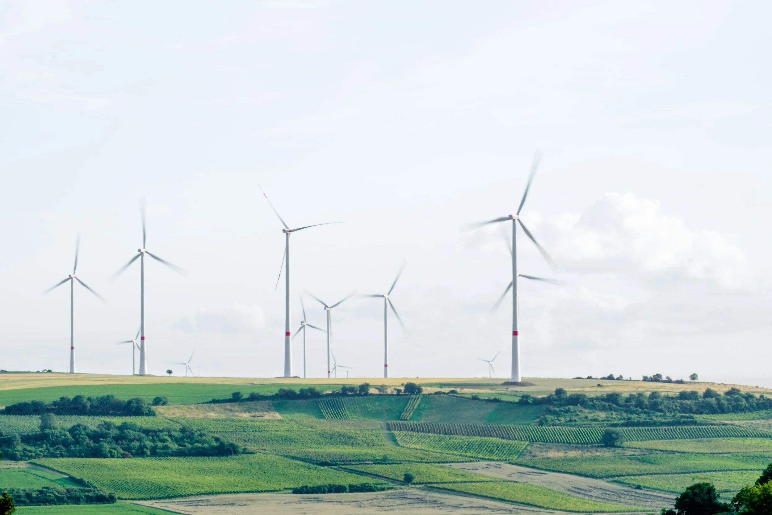 Wind turbines on green hills under a cloudy sky.