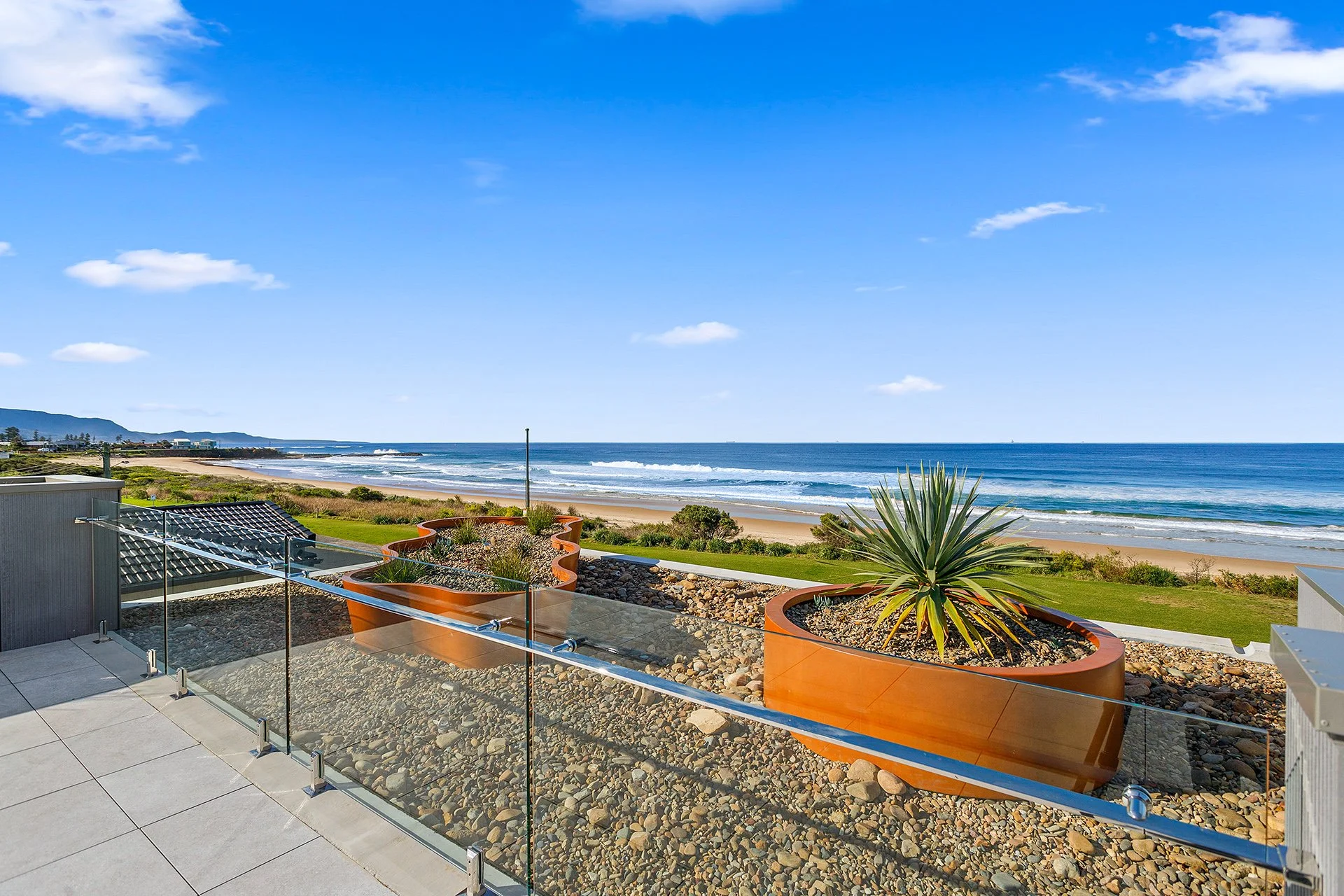 Apartment rooftop terrace featuring custom GRC planters with a rusted steel-inspired finish, overlooking the coastal landscape and ocean views of Woonona.