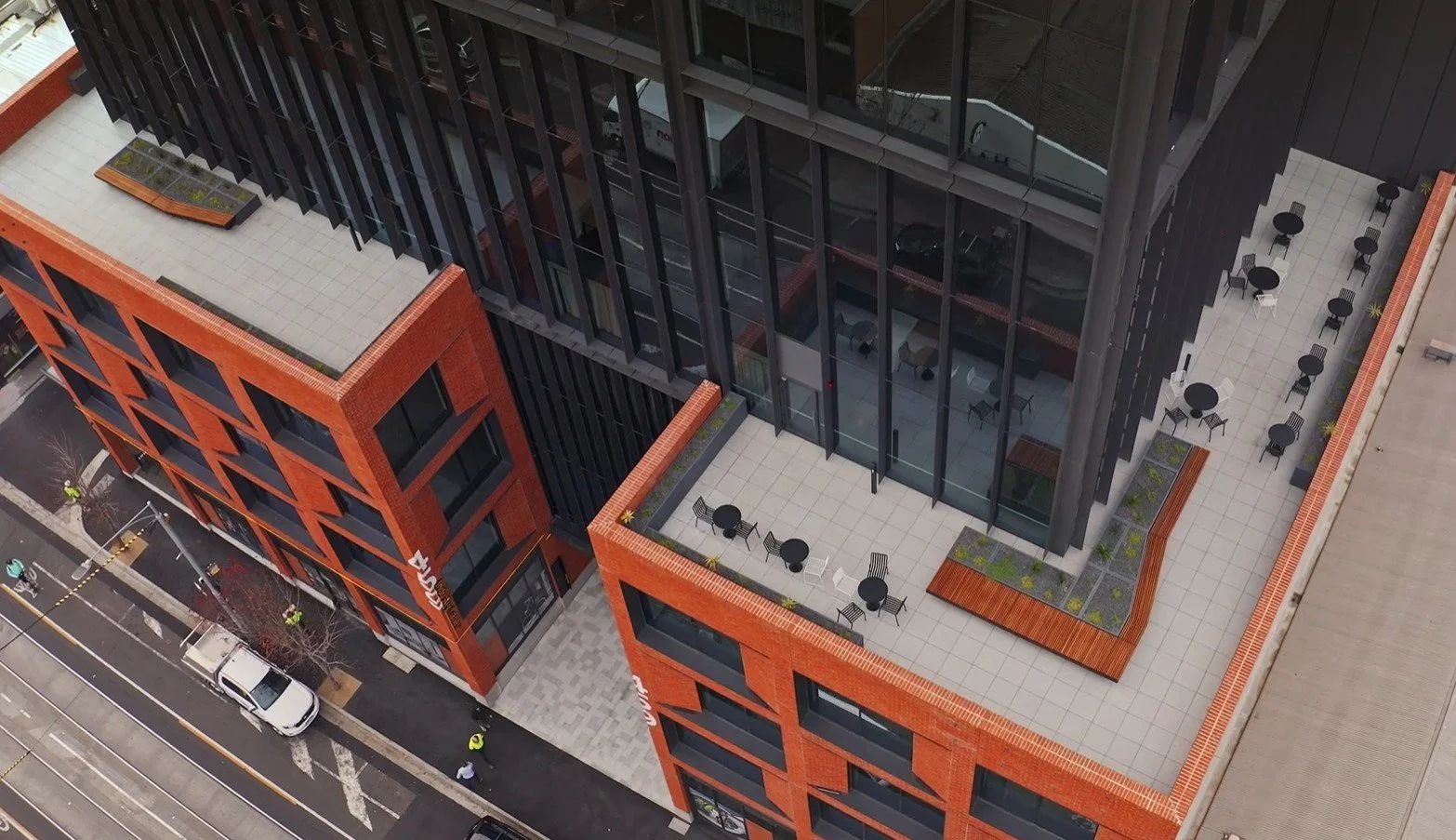 High-level aerial view of a commercial building rooftop showcasing rows of custom charcoal finished GRC planters and integrated bench planters across the upper terrace areas.
