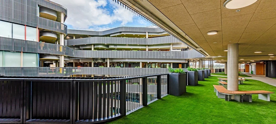 Contemporary college exterior featuring custom black GRC planter boxes positioned alongside vertical steel balustrades across multiple storeys.