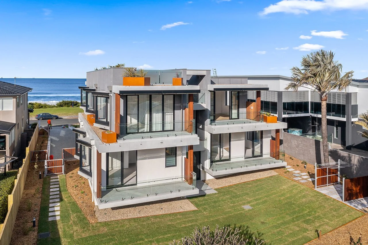 Elevated drone perspective of a coastal apartment building featuring uniquely shaped GRC planters positioned across multiple levels, enhancing the architectural facade.