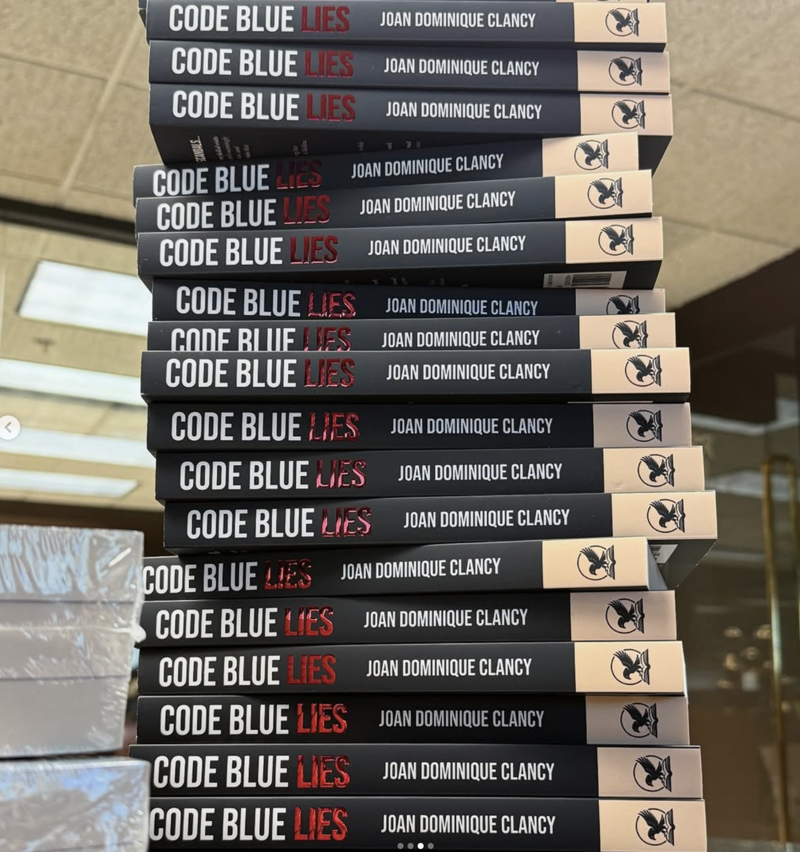 Stack of multiple copies of the book titled 'Code Blue Lies' by Joan Dominique Clancy arranged vertically on a table.