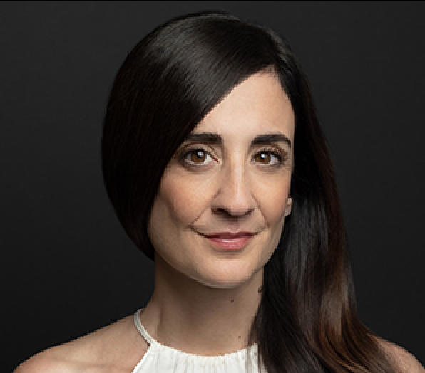 Portrait of a woman with long dark hair, wearing a white sleeveless top, against a dark background.