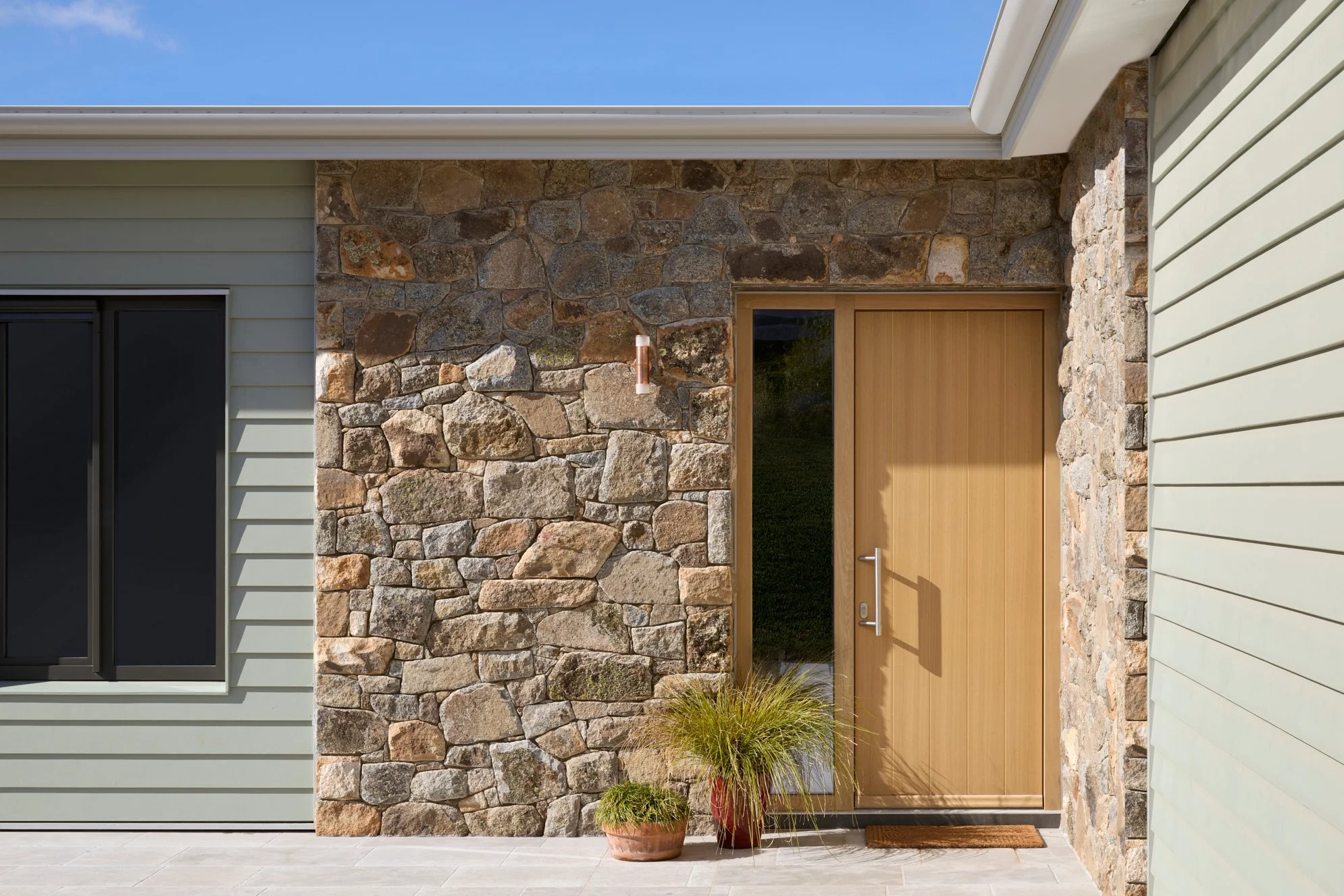 Weatherboard alpine home in Jindabyne with local granite stone facade and custom timber front door