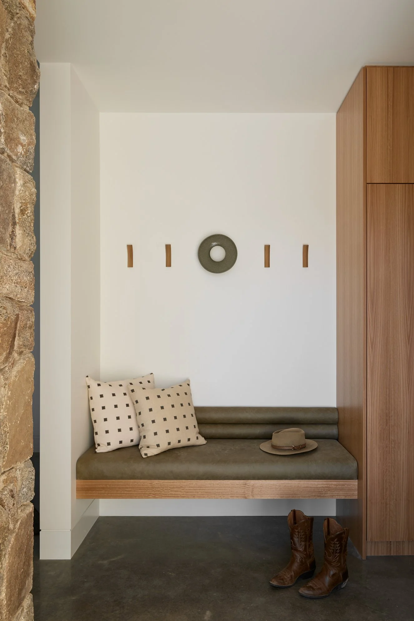 Alpine mudroom interior design in Jindabyne with timber veneer joinery, leather bench seat and local granite feature wall