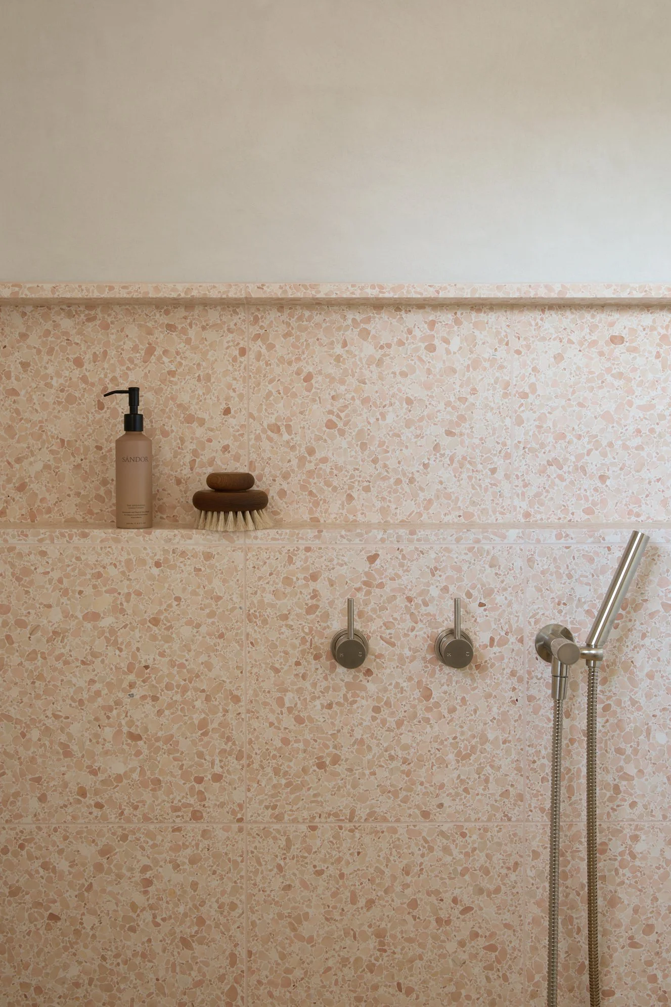 Dusty peach terrazzo bathroom design in Jindabyne with built-in shower niche and brushed nickel tapware