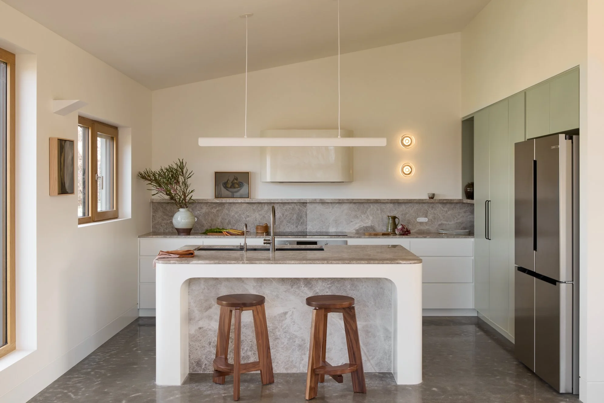 Luxury kitchen interior design in Jindabyne featuring natural stone benchtops, sculptural island and green cabinetry
