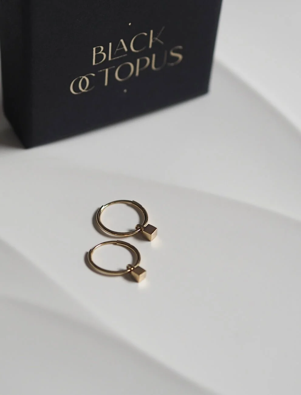 Gold mini hoop earrings with cube pendant