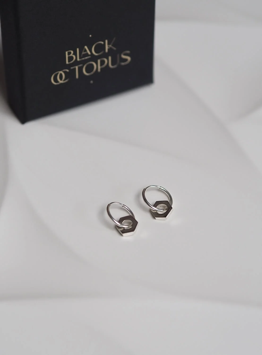 Silver endless hoop earrings with a hex nut pendant and box