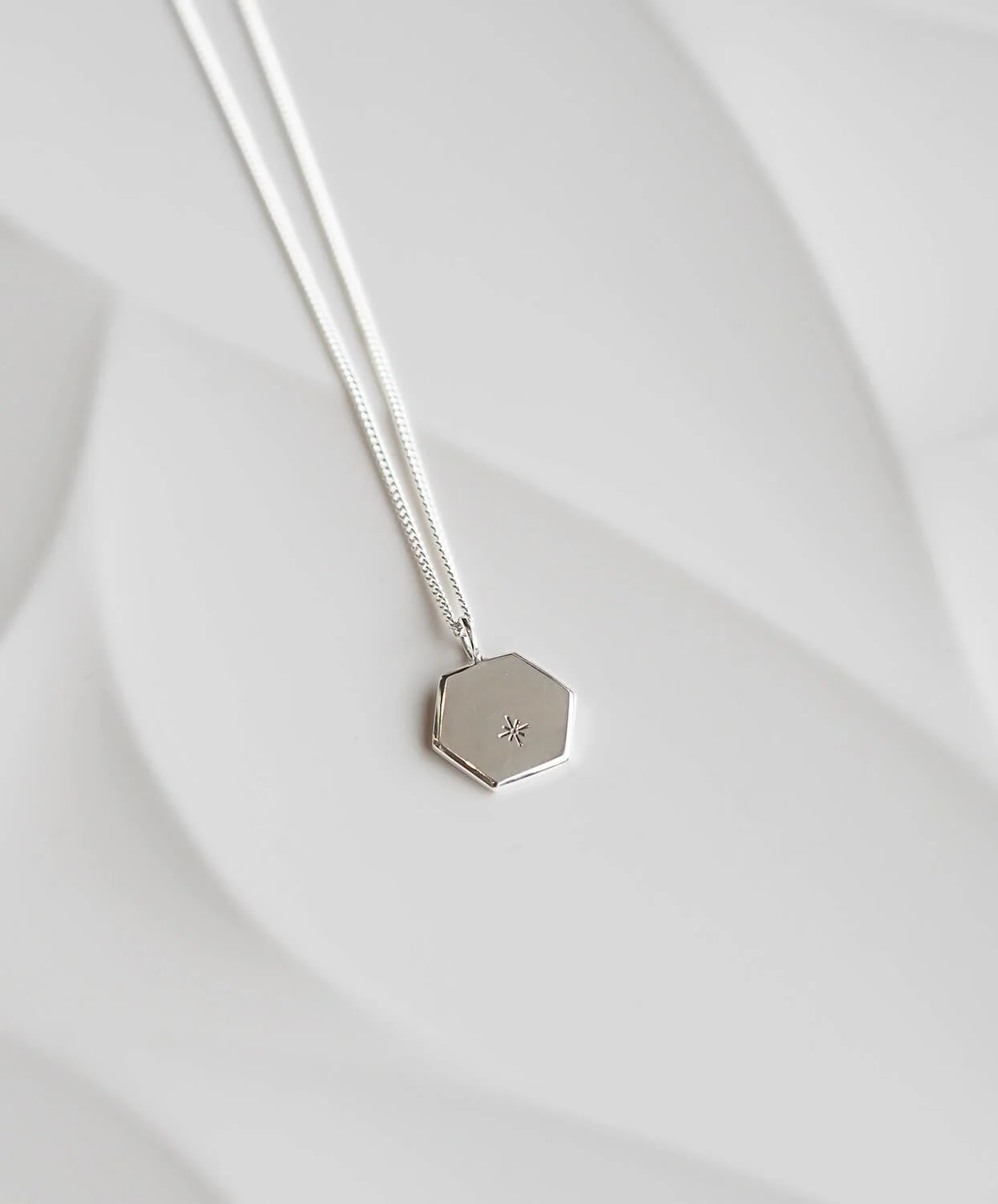 Silver hexagon pendant with celestial star design on curb chain