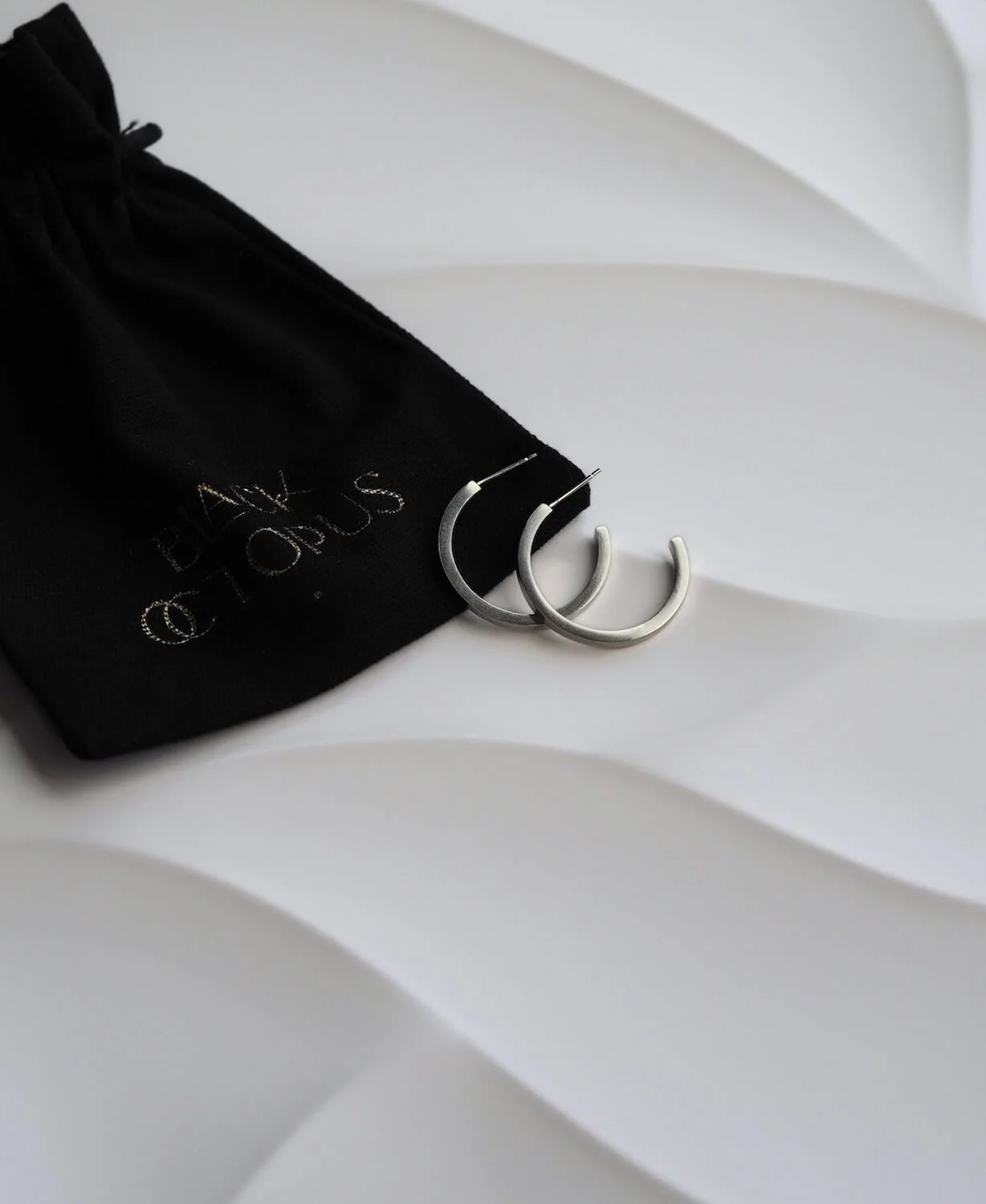Silver square hoop earrings with Black Octopus packaging