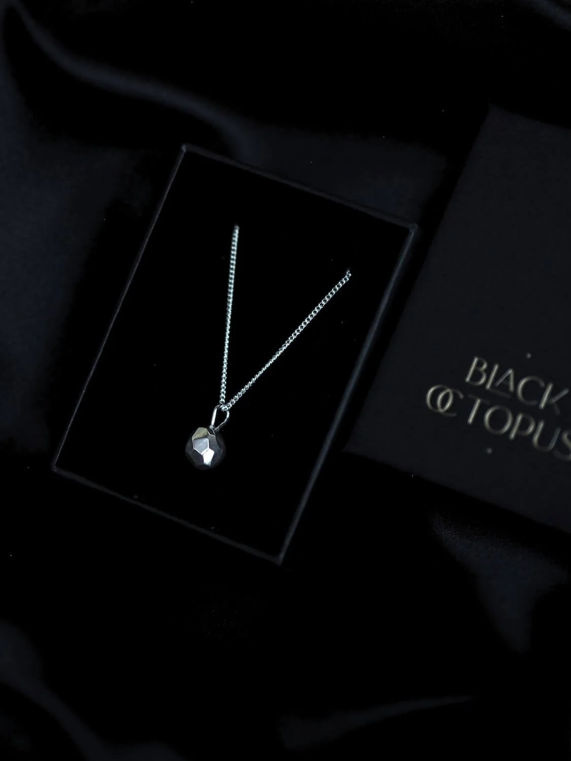 Silver faceted geometric pendant necklace with a luxury jewellery box