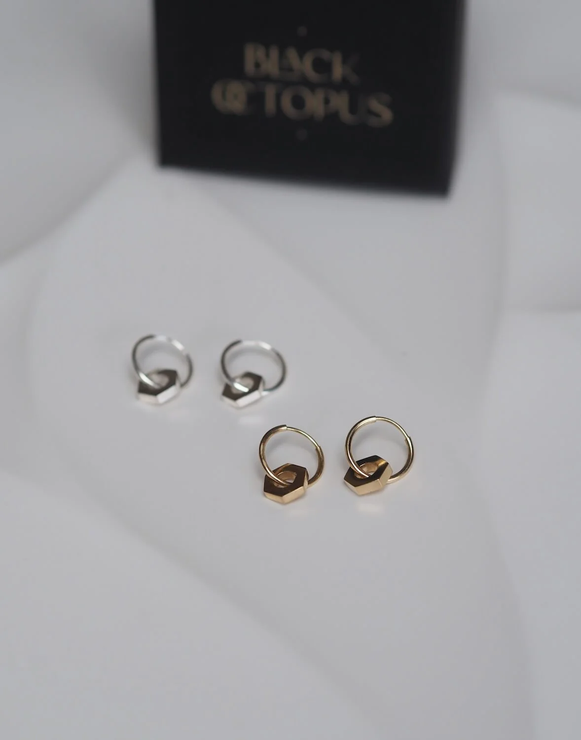 Silver and gold endless hoop earrings with a hex nut pendant and box