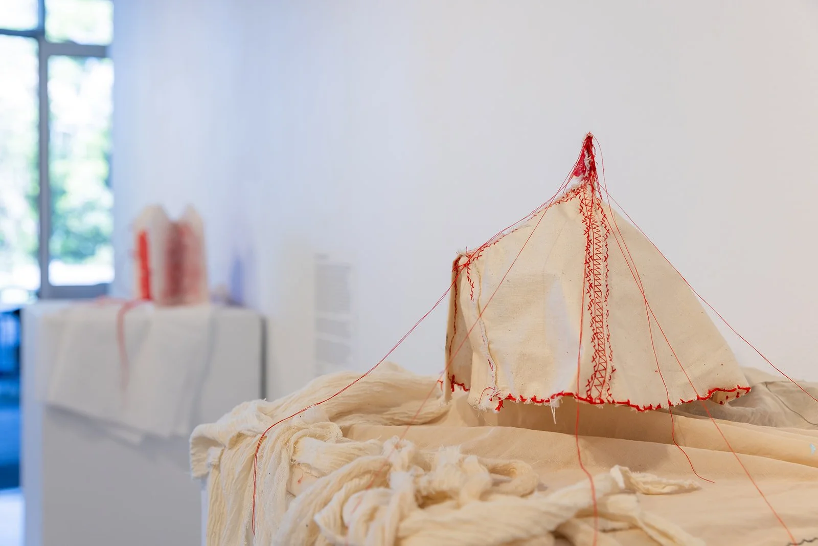 Chelsea Carkeet, Show Business I, 2024, calico, red cotton thread, electrical wire, cotton paper, armature wire, mdf board, dowel, gauze, 20cm x 20cm x 25cm. Photo by Robyn Wood. 